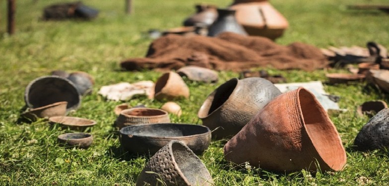 A range of historical clay pots laying on grass.