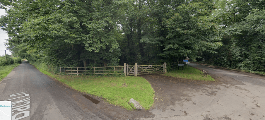 A rural lane with low level open timber fencing, formed of upright posts and three vertical bars