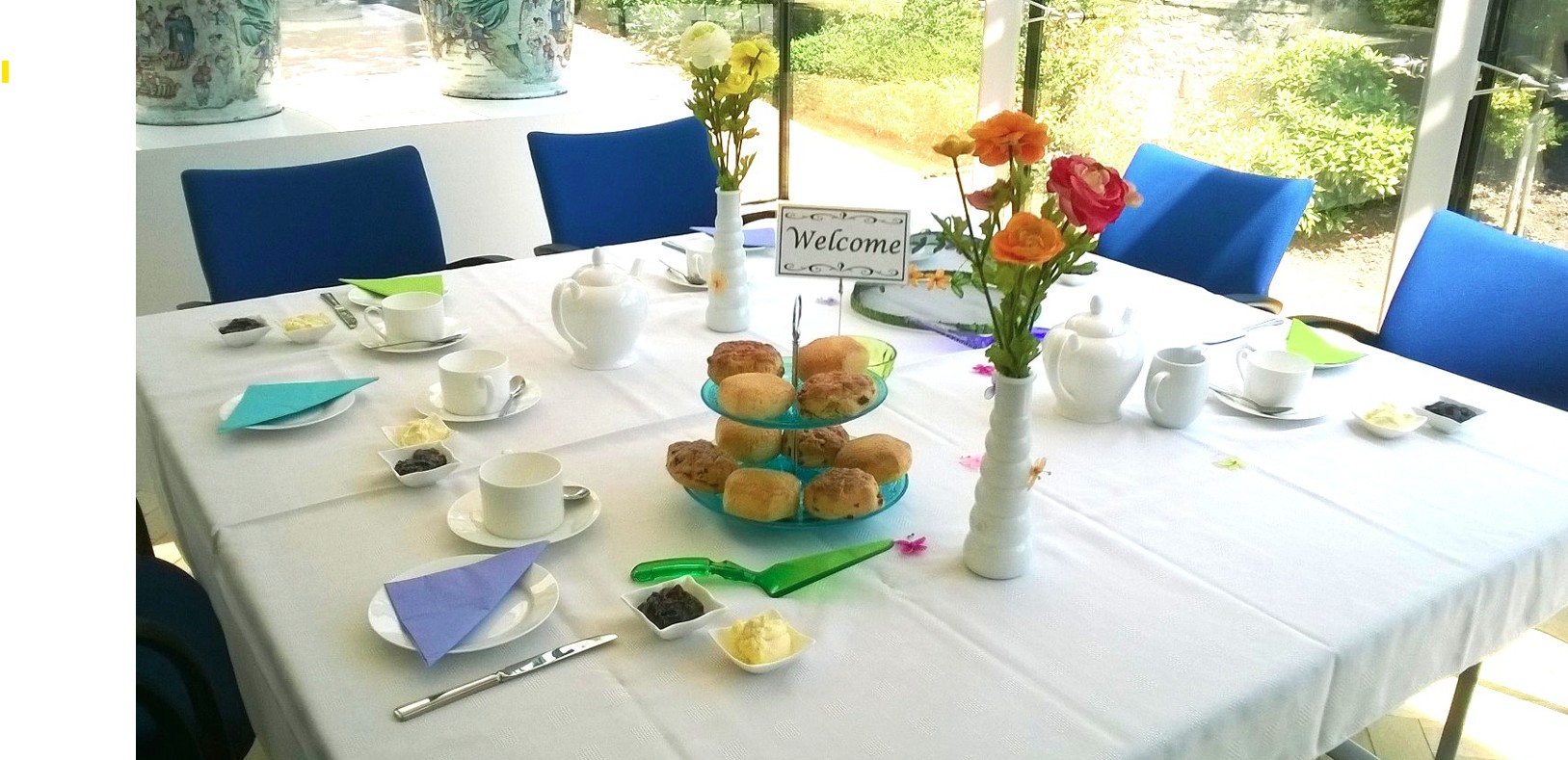 A table set for afternoon tea with scones, tea cups, and flowers.