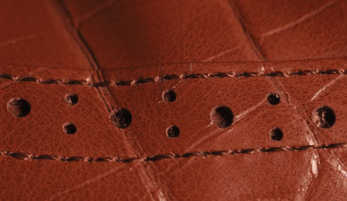 A close up of a piece of brown leather. It has been sewn with brown thread